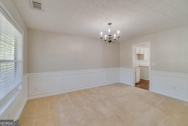 981 Charles Hall Dr, Dacula, GA 30019 - carpeted spare room featuring a textured ceiling, an inviting chandelier, wainscoting, and visible vents