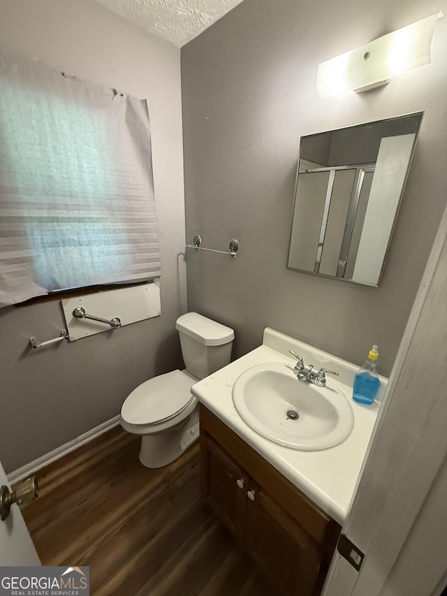 7260 Cox Rd, Cumming, GA 30028 - bathroom featuring vanity, toilet, a textured ceiling, a shower stall, and wood finished floors