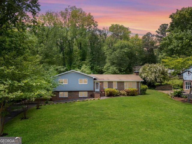 tri-level home with a lawn, entry steps, and brick siding