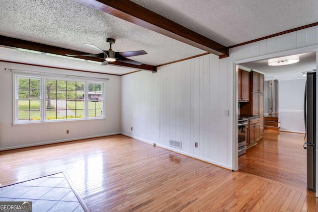spare room with a ceiling fan, a textured ceiling, visible vents, and light wood-style flooring