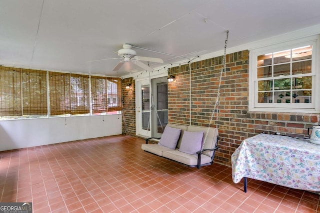 sunroom with a ceiling fan, brick wall, and a healthy amount of sunlight
