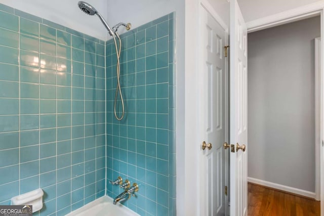 full bathroom with baseboards,  shower combination, and wood finished floors