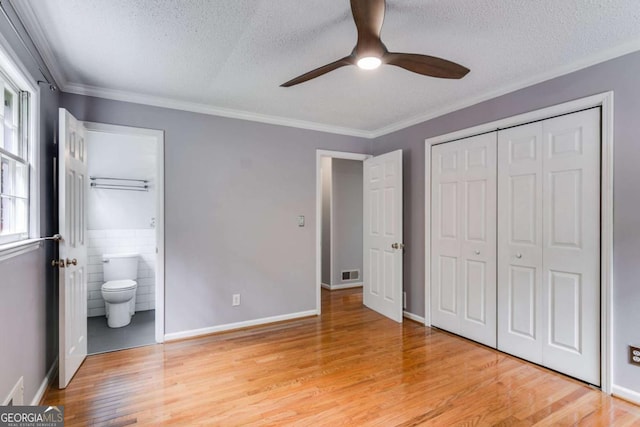 unfurnished bedroom with a textured ceiling, visible vents, light wood finished floors, and a closet