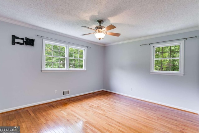 spare room featuring visible vents, crown molding, baseboards, a ceiling fan, and light wood finished floors
