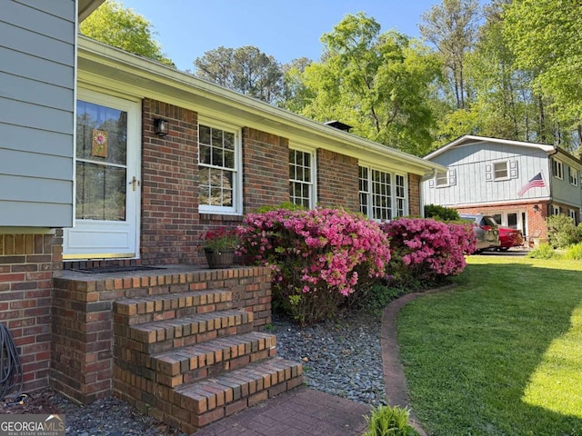 doorway to property with a yard and brick siding