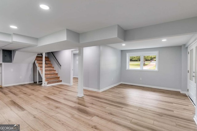 below grade area with electric panel, stairs, baseboards, recessed lighting, and light wood-style flooring
