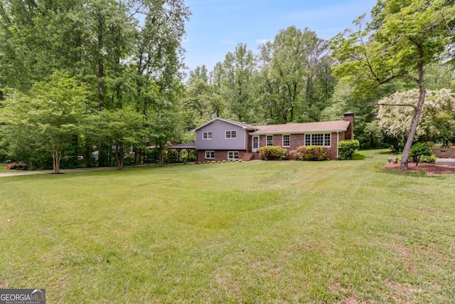 split level home featuring a chimney, a front lawn, and brick siding