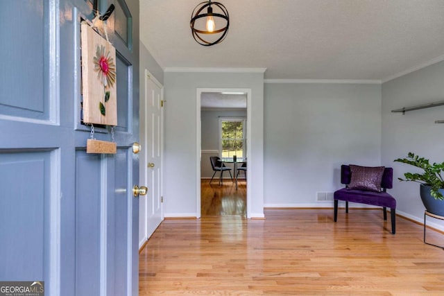 entrance foyer featuring crown molding, baseboards, light wood finished floors, and visible vents