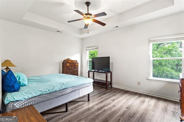 bedroom with visible vents, a raised ceiling, and wood finished floors