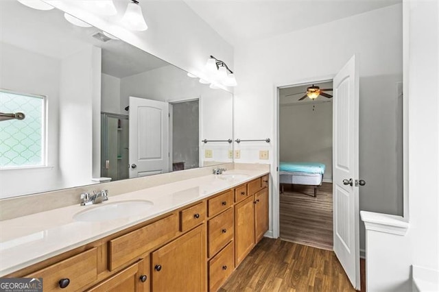 full bath with a sink, ceiling fan, double vanity, and wood finished floors