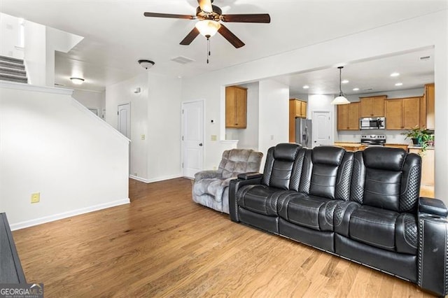 living area with baseboards, ceiling fan, light wood-type flooring, and visible vents