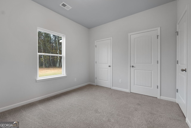 unfurnished bedroom with carpet floors, baseboards, and visible vents