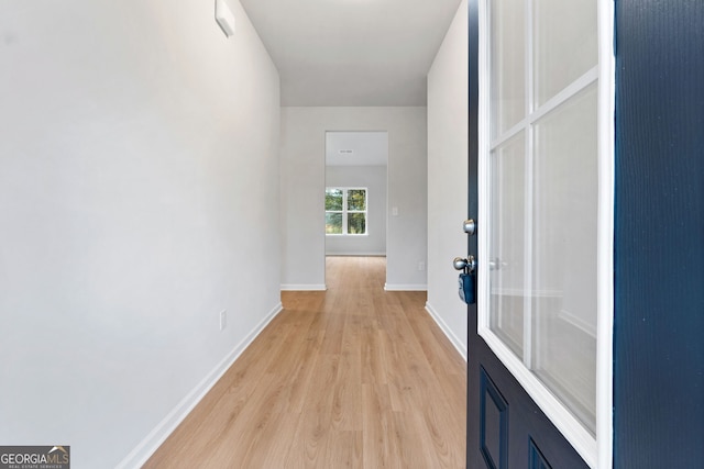 hall with baseboards and light wood finished floors