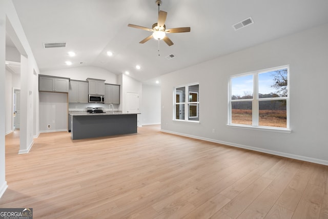 unfurnished living room with visible vents, ceiling fan, and vaulted ceiling
