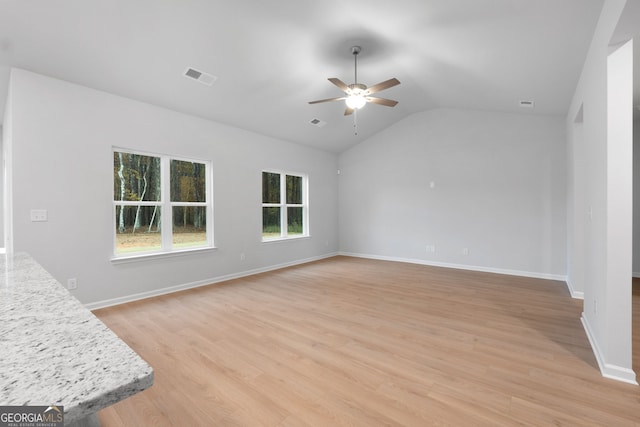 unfurnished living room featuring ceiling fan, vaulted ceiling, light wood-style flooring, and visible vents