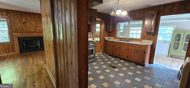 kitchen featuring a sink, electric range, wood walls, and light countertops