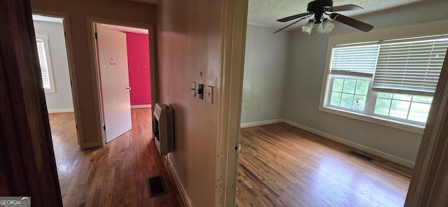 hall featuring visible vents, wood finished floors, and heating unit