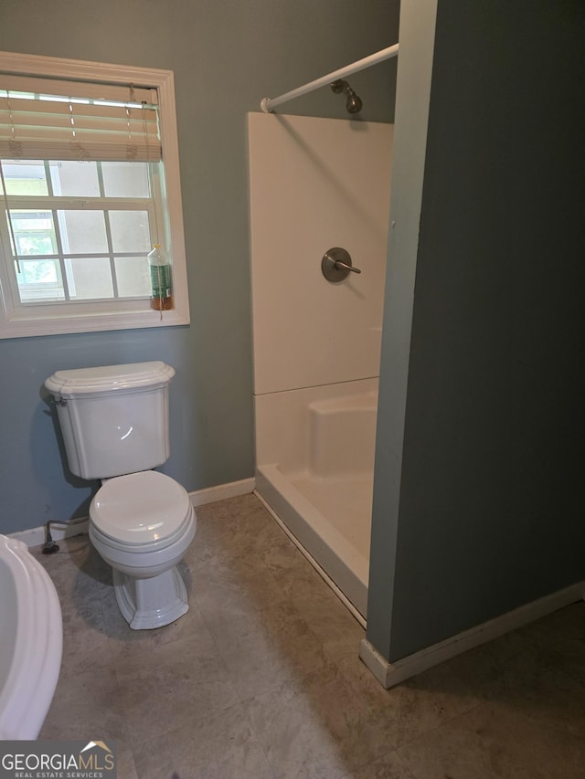 full bathroom with toilet, baseboards, and a stall shower