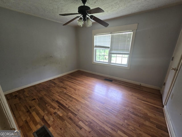 empty room with a textured ceiling, wood finished floors, and visible vents