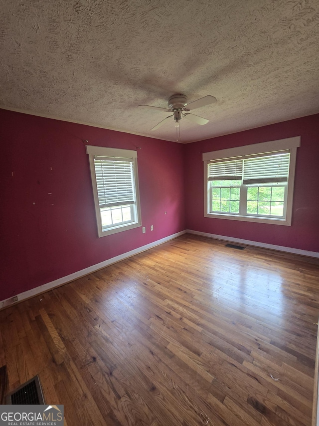 empty room featuring baseboards, a textured ceiling, ceiling fan, and wood finished floors