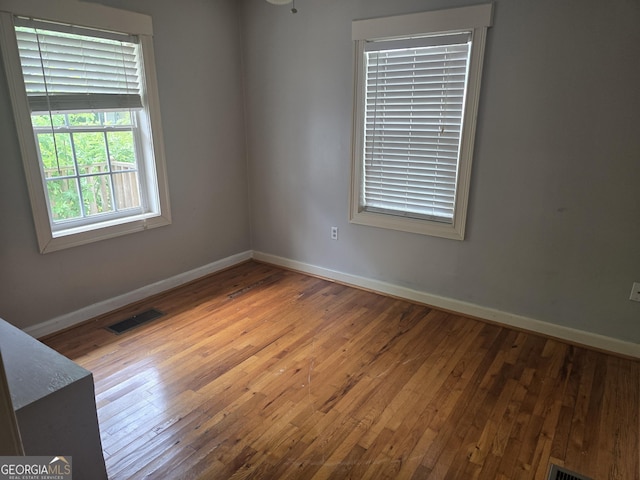 spare room featuring baseboards, visible vents, and hardwood / wood-style floors