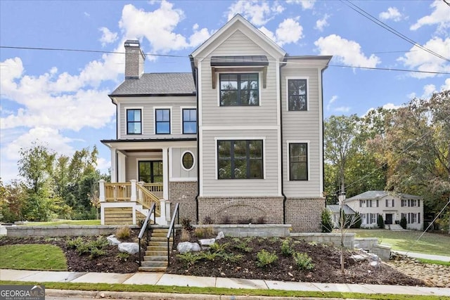 view of front of house featuring stairs, a chimney, a porch, and brick siding