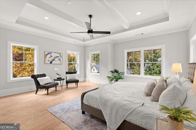 bedroom with baseboards, multiple windows, light wood-style flooring, and a raised ceiling