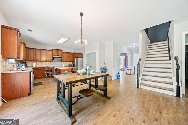 dining space with visible vents, stairs, light wood-style floors, arched walkways, and a notable chandelier
