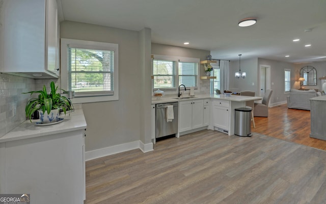 kitchen with backsplash, stainless steel dishwasher, a sink, baseboards, and open floor plan