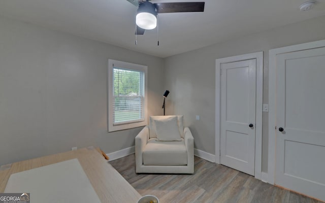 sitting room with baseboards, ceiling fan, and wood finished floors