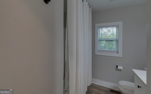bathroom featuring visible vents, wood finished floors, vanity, baseboards, and toilet