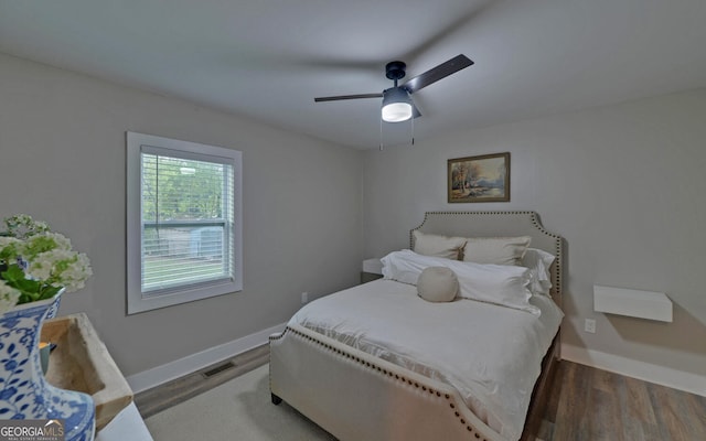 bedroom featuring visible vents, baseboards, ceiling fan, and wood finished floors