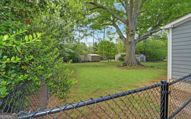 view of yard with fence, an outbuilding, and a storage unit