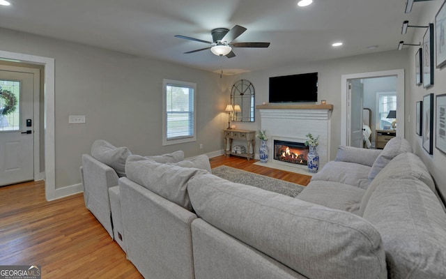 living area featuring recessed lighting, baseboards, a fireplace with flush hearth, and light wood finished floors