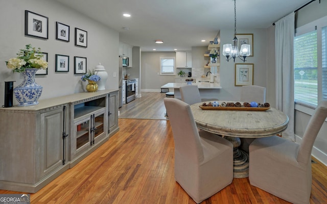 dining space with recessed lighting, baseboards, a notable chandelier, and light wood finished floors