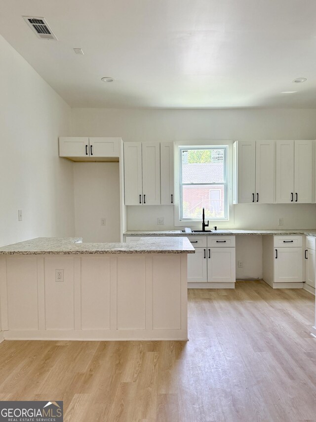 808 Center St, Macon, GA 31217 - kitchen featuring light wood-type flooring, a sink, light stone counters, and white cabinets