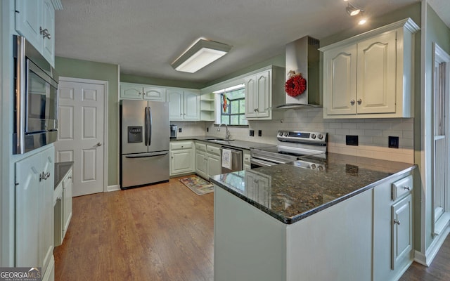 119 Ridgemore Cir, Toccoa, GA 30577 - kitchen with appliances with stainless steel finishes, wall chimney exhaust hood, a peninsula, wood finished floors, and dark stone countertops