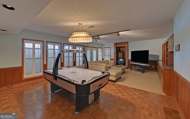 119 Ridgemore Cir, Toccoa, GA 30577 - rec room with a wood stove, a wainscoted wall, a textured ceiling, wooden walls, and track lighting