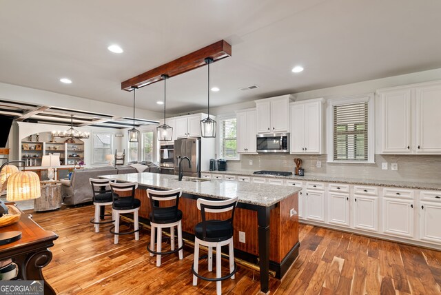 721 Paint Horse Dr, Canton, GA 30115 - kitchen featuring stainless steel appliances, open floor plan, a kitchen breakfast bar, beam ceiling, and an island with sink