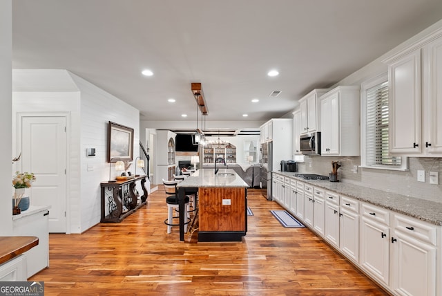 721 Paint Horse Dr, Canton, GA 30115 - kitchen with appliances with stainless steel finishes, a sink, white cabinetry, light wood-type flooring, and a kitchen bar