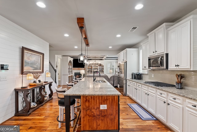 721 Paint Horse Dr, Canton, GA 30115 - kitchen featuring appliances with stainless steel finishes, a sink, open floor plan, white cabinetry, and light wood-style flooring
