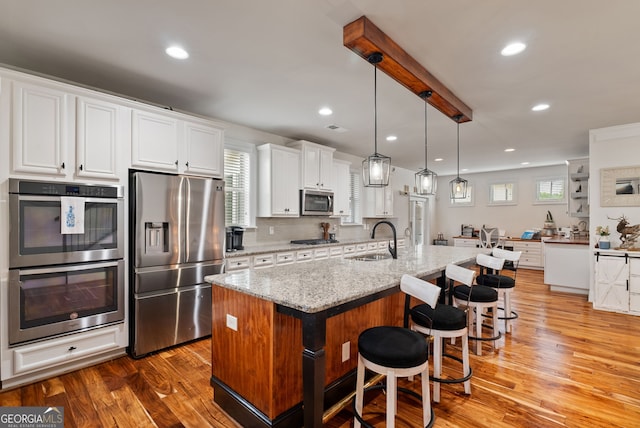 721 Paint Horse Dr, Canton, GA 30115 - kitchen featuring stainless steel appliances, a sink, wood finished floors, white cabinets, and a breakfast bar area