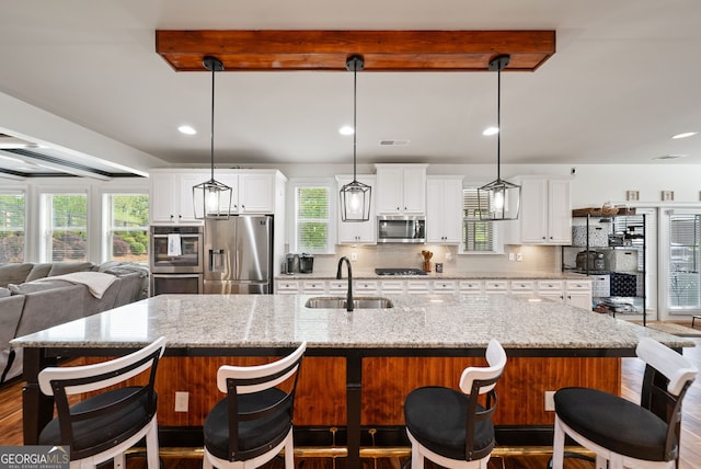 721 Paint Horse Dr, Canton, GA 30115 - kitchen with stainless steel appliances, a sink, white cabinetry, a large island, and a breakfast bar