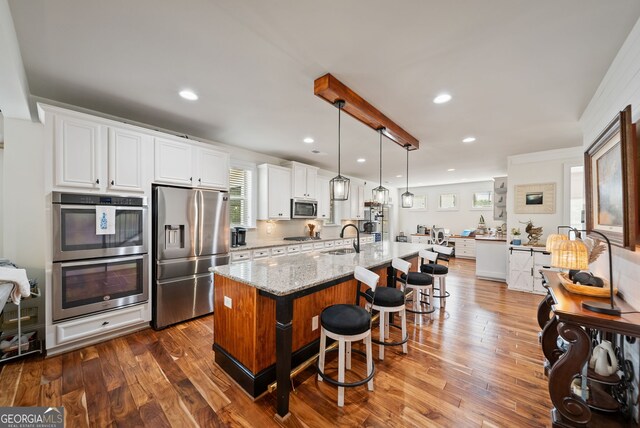 721 Paint Horse Dr, Canton, GA 30115 - kitchen with stainless steel appliances, a sink, a breakfast bar area, white cabinetry, and light stone counters