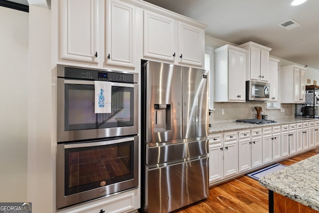 721 Paint Horse Dr, Canton, GA 30115 - kitchen with stainless steel appliances, wood finished floors, white cabinetry, tasteful backsplash, and light stone countertops