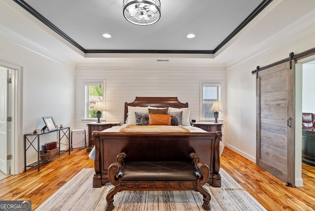 721 Paint Horse Dr, Canton, GA 30115 - bedroom with light wood-style floors, a barn door, ornamental molding, a raised ceiling, and baseboards