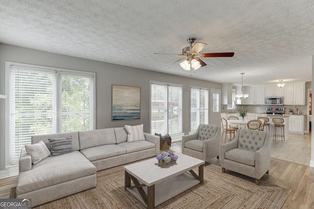 5922 Terrace Lake Pt, Flowery Branch, GA 30542 - living room featuring a ceiling fan, healthy amount of natural light, light wood finished floors, a chandelier, and a textured ceiling