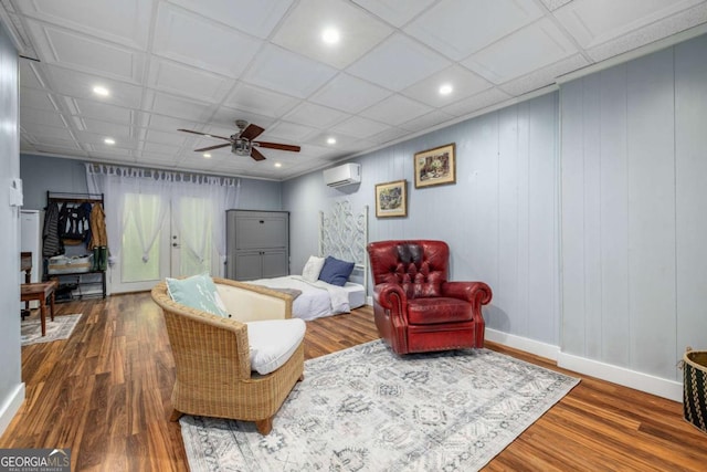living area featuring a ceiling fan, baseboards, recessed lighting, a wall unit AC, and wood finished floors
