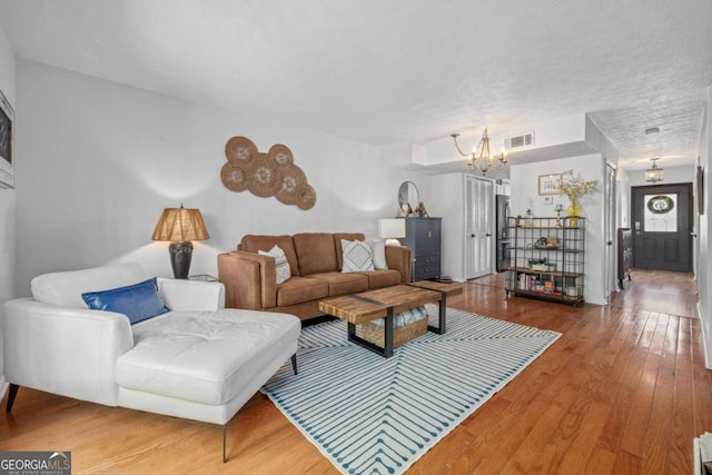 living area with visible vents, wood finished floors, and a chandelier