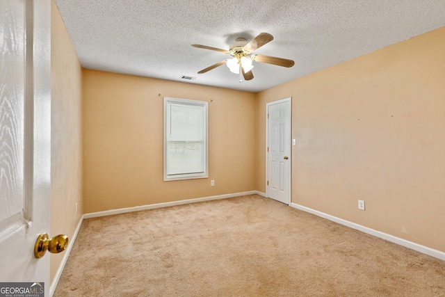 carpeted spare room featuring baseboards, a ceiling fan, and a textured ceiling